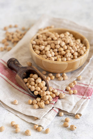 Bowl of raw dry chickpea with a scoop top view on a kitchen towel