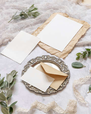 Wedding stationery set with envelope laying on a marble table decorated with eucalyptus branches and ribbons. Mock-up scene with blank paper greeting cards. Feminine close upの写真素材