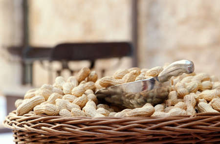 Wicker basket of raw organic peanuts in shell with metal scoop at outdoor market, copy space. Unpeeled groundnuts for sale at local marketplace, closeup view. Healthy vegeratian foodの写真素材