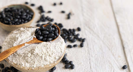 Ceramic bowls with black beans flour and dried beans with a wooden spoon closeup. Healthy eating and vegetarian concept. Traditional Latin American cousin ingredientの写真素材