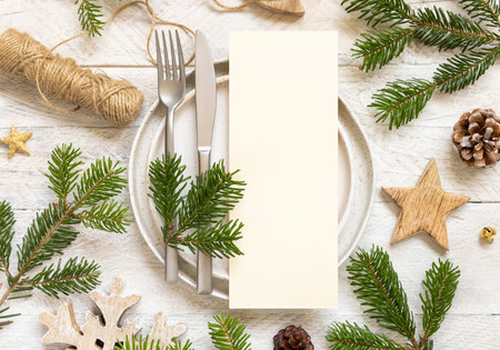 Festive table setting of plates, cutlery and fir tree branches top view. Mockup of Christmas or New Year menu on white wooden table, copy space. Winter wedding, restaurant holiday cateringの写真素材