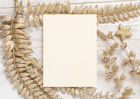 Blank greeting card and golden leaves on white wooden table top view. Mockup of Christmas or New Year card, copy space. Winter holiday conceptの写真素材