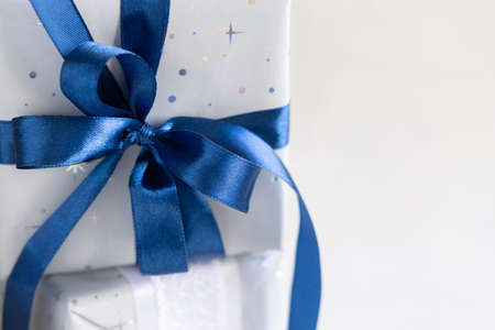 Wrapped Christmas present with a blue ribbon bow close up. Grey and blue winter composition with Gift box, copy spaceの写真素材