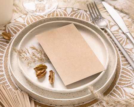 Wedding table place with blank card on bohemian placemat close up. Boho wedding card mockup. Tropical beige template with dried palm leaves and pampas grass, place fot textの写真素材