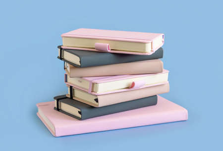 Stack of pink, beige and grey notebooks on light blue closeup. Textbook mockup. Educational, business and organizing conceptの写真素材