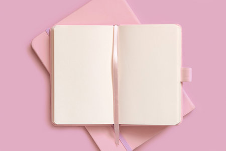Opened pink notebook on on other one on light pink table top view. Textbook mockup, planner cover...