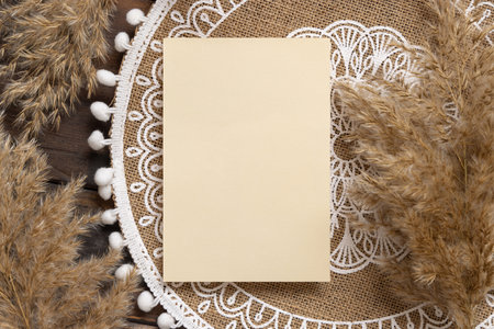Blank wedding card on bohemian jute placemat near pampas grass top view. Boho rustic scene with greeting or Invitation vertical  card mockup, flat lay.の写真素材