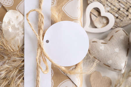 Valentines kraft paper wrapped present with round gift tag near hearts and pampas grass close up. Spring scene with blank label. Rustic, cottage chic or bohemian mockup, copy spaceの写真素材