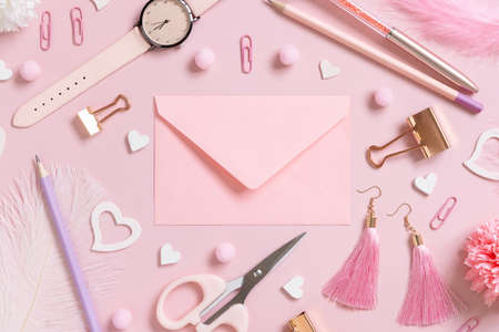 Pink envelope, school accessories and hearts on pastel pink top view, blank envelope mockup. Girly workplace. Back to school and valentines day conceptsの写真素材