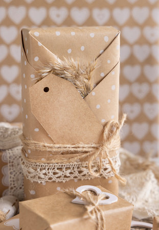 Valentines kraft paper wrapped present with vertical gift tag, hearts and pampas grass close up. Spring scene with blank label. Rustic, cottage chic or bohemian mockup, copy spaceの写真素材