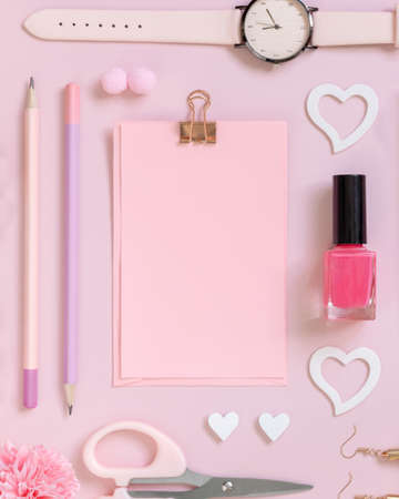 Pink paper card with clip, school girlish accessories and hearts on pastel pink top view, blank card mockup. Girly workplace. Back to school and valentines day conceptsの写真素材