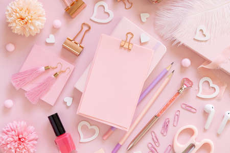 Pink paper card with clip, school girlish accessories and hearts on pastel pink top view, blank card mockup. Girly workplace. Back to school and valentines day conceptsの写真素材