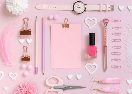 Pink paper card with clip, school girlish accessories and hearts on pastel pink top view, blank card mockup. Girly workplace. Back to school and valentines day conceptsの写真素材
