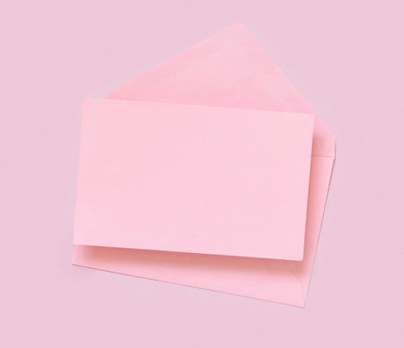 Pink paper card and envelope on pink top view. Minimal scene with blank card mockup. Educational and girly concept,  space for text.の写真素材