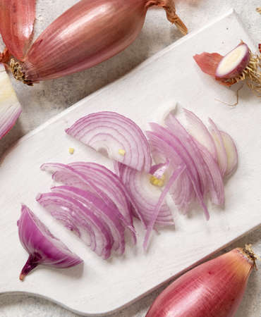 Sliced Red tropea onions on a white board top view. Traditional local south italian vegetable. Cooking process in home kitchenの写真素材