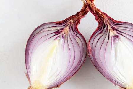 Half of Red tropea onions on a white table close up. Traditional local south italian vegetable. Cooking process in home kitchenの写真素材