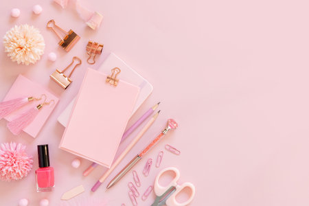 Paper with a clip and Pink school accessories on pastel pink, top view, mockup. Girly workplace with scissors, pencils, pen, paperclips, earrings and nail polish. Back to school conceptの写真素材
