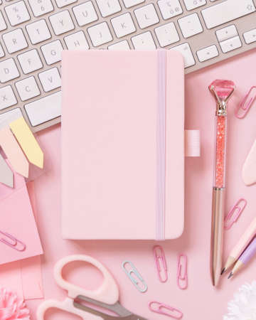 Hardcover notebook, Pink school accessories and keyboard on light pink, Top view, textbook mockup. Girly workplace with notebook, scissors, pencil, pen, paperclips, cards and watch. Back to schoolの写真素材
