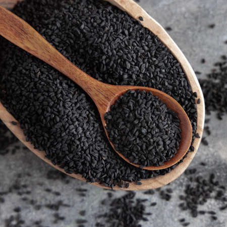 Indian spice Black cumin (nigella sativa or kalonji) seeds in bowl with spoon on grey table top view. Traditional medicine, healthy and vegetarian food concept.の写真素材