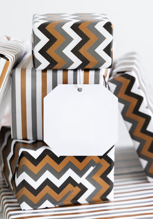 Present with blank gift tag close up. Gift boxes wrapped in Striped and chevron geometric paper. Christmas, New Year, Birthday, Anniversary label mockupの写真素材