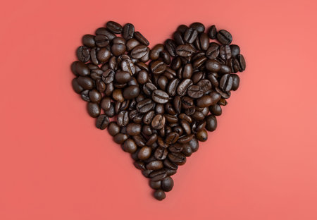 Heart made of Roasted Coffee beans top view on pink background. Represent breakfast, love, energy, freshness or aromaの写真素材