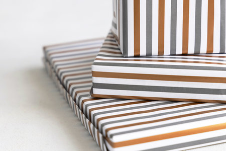 Presents Wrapped in striped geometric paper on white table close up. Christmas, New Year, Birthday, Anniversary  conceptの写真素材