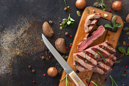 Grilled beef fillet steaks on dark table close up top view. Portioned filet mignon with spices and herbs. Concept of summer food, meat eaters.の写真素材
