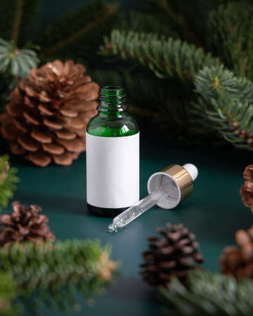 Green Pipette Dropper Bottles with blank label near fir branches and pine cones close up. Brand packaging mockup. Skincare beauty product, cream or serum. Natural cosmetics conceptの写真素材