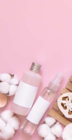 Organic Homemade Cosmetics in plastic tubes and bottles and cotton flowers on pink flat lay, copy space. Top view of natural beauty products for bath, massage or spa salonの写真素材