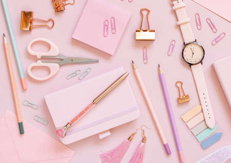 Pink school accessories and stationery on pastel pink background Top view. Girly workplace with notebook, scissors, pencils, pens, sticky note paper, clips and watch. Back to school conceptの写真素材