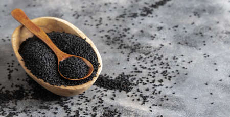 Indian spice Black cumin (nigella sativa or kalonji) seeds in bowl with spoon on grey table close up with copy space. Traditional medicine, healthy and vegetarian food concept.の写真素材