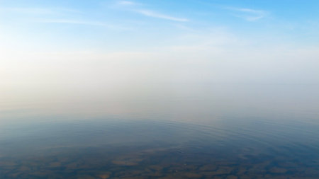 Calm minimalist landscape with smooth lake surface with calm water with horizon with clear blue sky, simple beautiful calm natural blue backgroundの写真素材