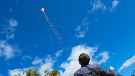 flying a kite in a strong wind. In the background, a kite flies high in the sky.の写真素材