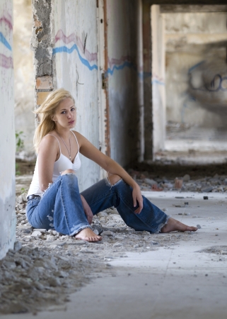 portrait of beautiful  blonde girl sitting near wall の写真素材