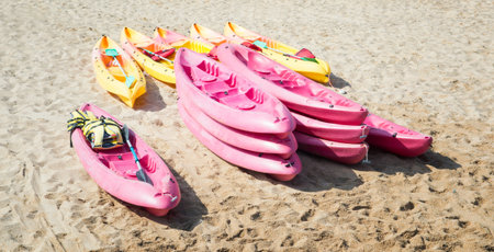 Pink and yellow kayaks on the beachの写真素材