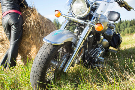 Motorcyclist resting at haystack in a field sunny day