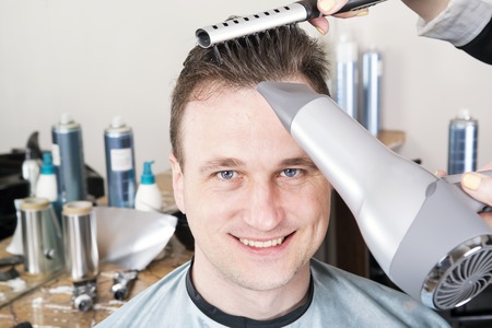 Barber cuts hair of handsome satisfied client in professional  hairdressing salon.の写真素材