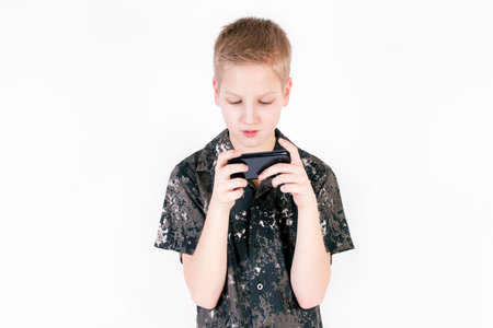 Young caucasian boy browsing snapshots or video on a smart phone isolated on white background.の写真素材