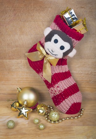 Christmas red sock with monkey and any gold balls and star isolated on wood surface, next year symbol like a christmas background.の写真素材