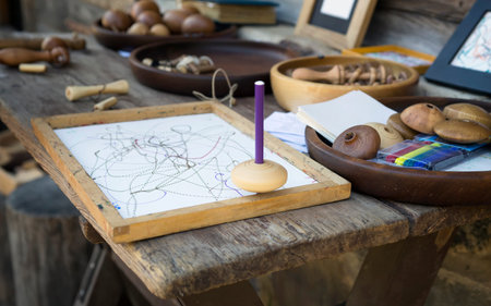 Wooden whirligig on wooden board with white leaf of paper. Pencil inserted into the wooden...