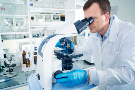 Portrait of caucasian male chemist scientific researcher using microscope in the laboratory interior