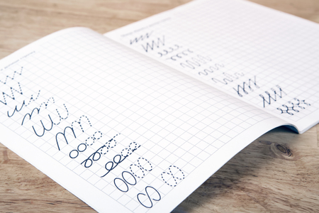 Words writing on exercise books of primary school students, Close-up photo on wooden surface. Education concept.の写真素材