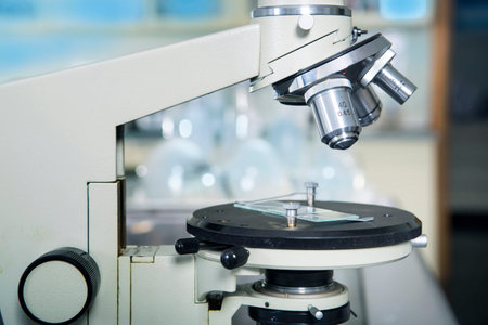 Photo of a professional ocular laboratory microscope with stereo eyepiece in laboratory interior.