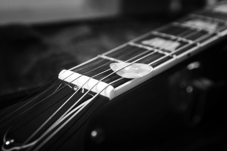 Acoustic guitar with piectrum close up in dark backgroundの写真素材