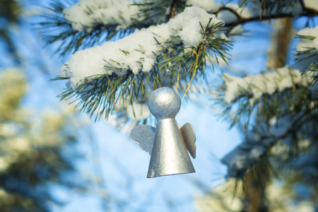 Silver angel from a cardboard   on a fir-tree branch in the snow-covered wood. Christmas backgroundの写真素材