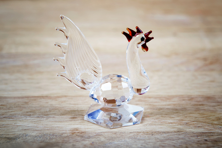 Figure of a glass rooster a symbol of 2017 on a wooden backgroundの写真素材