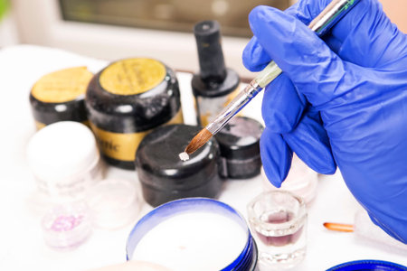 Manicure in beauty shop. Acrylic nails. Master make nail extension. Acrylic nail polish jar bottle closeup の写真素材