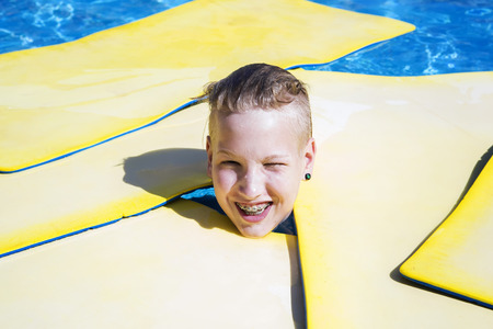 Teenager swims on a mat  in the poolの写真素材