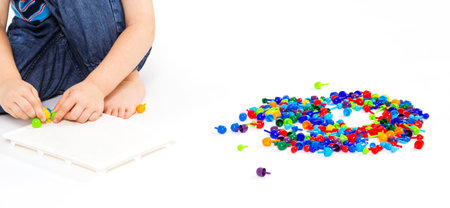 Little boy plays with mosaic on the white background.