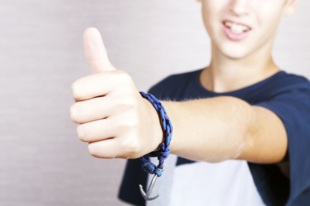 Portrait of smiling blonde boy lifting the big finger of a hand upwards.の写真素材